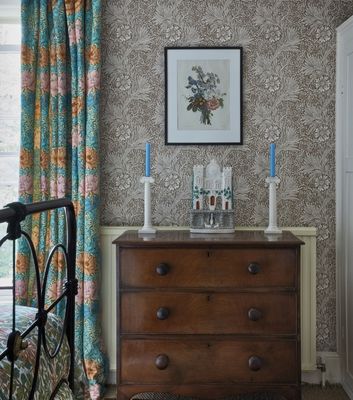 Tapeten Marigold från William Morris & Co, en tapet med ett monokromt mönster som här kompletteras med färgglada detaljer och möbler i mörkt trä.