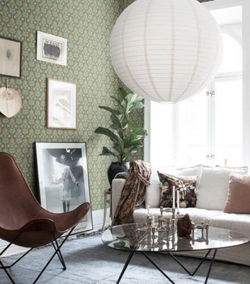 Vardagsrum med en grön tapet som här blandats upp med moderna och trendiga material och möbler som tex soffan i linne, skinnstol och glasbord, här tapeten Othilia från Midbec.